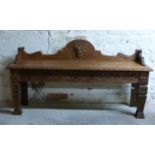 A carved oak hall or window seat with lion mask pediment and legs,