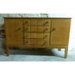 Gordon Russell light oak sideboard with two doors either side of four straight drawers raised on