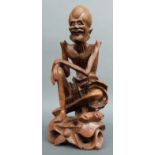 A carved wooden Chinese figure of an emaciated immortal with bone teeth,