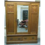 An Art Nouveau inlaid oak wardrobe with bevelled mirror door and two drawers,