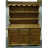 An elm dresser with three drawers over cupboards with plate rack above and brass handles,