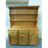 A pine dresser having three drawers and three cupboards with plate rack above,