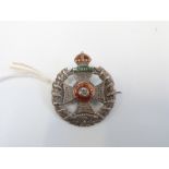 A silver badge marked sterling, reading 'Waterloo' in a green enamel tablet,