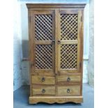 A modern hardwood cupboard with lattice fronted doors and four drawers below,