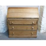 A pine bureau, the fall flap opening to reveal pigeon holes, the base fitted three long drawers,