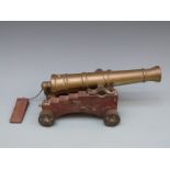 A late 19th/early 20thC bronze desk cannon and wooden carriage with bronze wheels with 10 inch