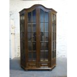 An oak display cabinet with glazed doors and sloping side panels,