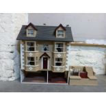 A three storey dolls' house with dormer windows and annexe,