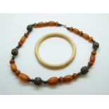 An amber necklace with white metal filigree fittings (61g) & a carved ivory bangle