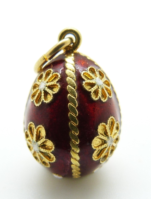An 18ct gold enamel egg pendant decorated with flowers on a red enamel ground and decorated with