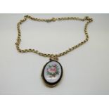 A Victorian oval locket with oval enamel plaque depicting roses on gilt textured chain