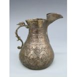 A Middle Eastern or similar white metal jug with embossed decoration, height 9.