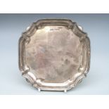 A Walker & Hall George V hallmarked silver salver with shaped edge, raise on four squat ball feet,