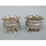 A pair of Victorian hallmarked silver pedestal salts with wrythen decoration and crimped rims,