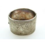 A white metal Victorian bangle with chased foliate design