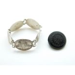 A silver bracelet made up of plaques depicting tourist areas in London and a jet brooch