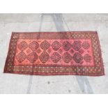 An Afghan rug with central pattern of fourteen large guls on a red ground,