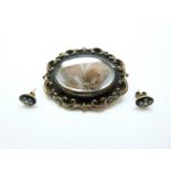 A Victorian brooch set with black enamel, the glass compartment to the centre set with hair,