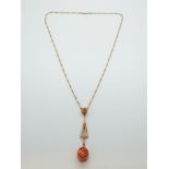 A 15ct gold necklace with a drop pendant set with two rose coral carvings