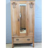 A satinwood Art Nouveau wardrobe with bevelled mirror door and single drawer below,