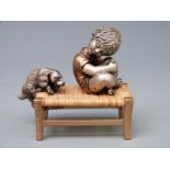 A novelty white metal or similar and bronzed model of a boy and a dog on a rush seated stool,