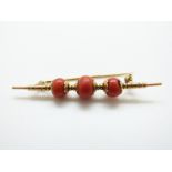 An 18ct gold brooch set with three coral beads,