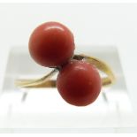 A yellow metal ring set with two coral cabochons, size N/O,