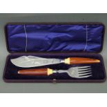 A cased set of silver plated fish servers with engraved decoration and stained ivory handles