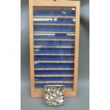 A glass fronted wooden display case with approximately 55 spoons,