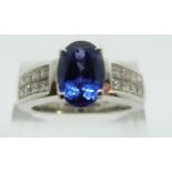 An 18ct white gold ring set with tanzanite and princess cut diamonds to the shoulders, size P, 9.