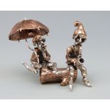 A novelty part white metal figure group of two bearded men, one with umbrella the other a pipe,