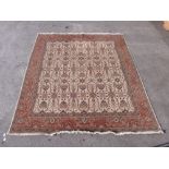 A cream wool rug with rust coloured border and geometric design,