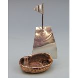 A novelty miniature boat, the hull formed as a walnut shell with white metal sail, height 73mm,