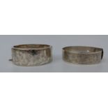 A hallmarked silver bangle with chased foliate design and a silver bangle with scrolling design,