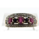 A 9ct gold ring set with black diamonds and rubies, size P, 3.