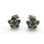 A pair of white metal earrings set with emeralds