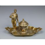 A brass inkwell decorated with a jockey or similar figure,