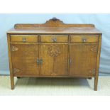 An oak sideboard with foliate decoration to doors,