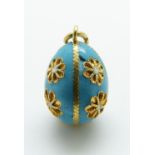 An 18ct gold enamel egg pendant decorated with flowers on a blue enamel ground,