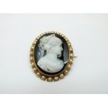 A Victorian brooch set with a hardstone cameo depicting a woman,