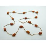 A Victorian yellow metal necklace set with barrel-shaped amber beads, the largest approximately 1.