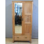 A satinwood wardrobe with bevelled mirror door and single drawer below,