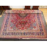 A Persian red ground rug with central motif and blue border,