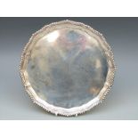 A hallmarked silver salver with rope twist rim, raised on three scroll feet,