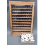 A glass fronted wooden display case with approximately 190 thimbles,