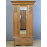 A satinwood Art Nouveau wardrobe with bevelled mirror door and single drawer below,