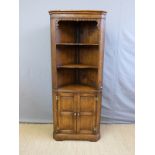 A reproduction oak corner cupboard with display shelves and lower cupboard,