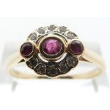 A 14ct gold ring set with three central rubies in an oval diamond surround,