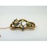 A 9ct gold Art Nouveau brooch in the form of a flower set with enamel, seed pearls and a sapphire,