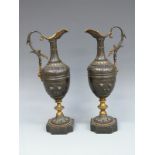 A pair of 19thC bronze pedestal ewers with gilt and foliate decoration raised on beaded bases,
